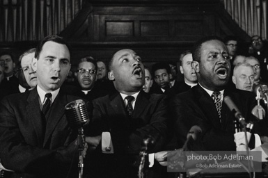 King leads the singing of “We Shall Overcome” after eulogizing a slain civil rights crusader, the Reverend James Reeb, Brown Chapel, Selma, Alabama. 1965.