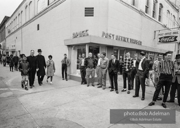 Hecklers stand together shouting insults as demostrators and participants of a voting rights drive pass by. Selma, AL, 1965.