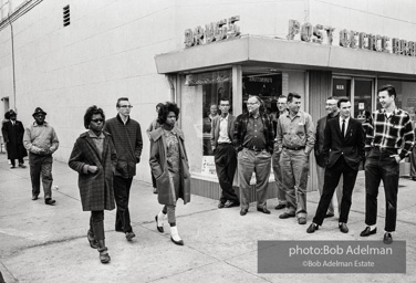 Hecklers stand together shouting insults as demostrators and participants of a voting rights drive pass by. Selma, AL, 1965.