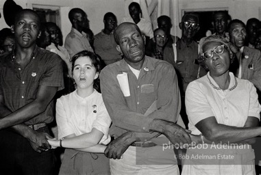 Joining the flock, West Feliciana Parish, Louisiana. 1963

“In West Feliciana, an overwhelmingly black parish where no person of color had voted in the twentieth century, volunteer Mimi Feingold urged members of a church congregation to try to vote. She then joined hands with them to sing, ‘This Little Light of Mine.