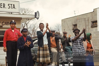 The marchers are cheered by workers at a cab stand that was one of the bulwarks of the Montgomery bus boycott ten years earlier, Montgomery, Alabama. 1965.