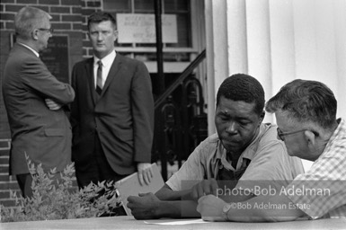 Having his say: An illiterate first-time voter casts his ballot orally under the provisions of the Voting Rights Act as an FBI agent looks on,  Camden,   Alabama.  1966-

“During the debate on the Voting Rights Act of 1965, Dr. King argued strenuously that illiterate blacks should have the right to cast their ballots orally. He justified his position by pointing out the poor quality of education offered in separate-but-equal schools.”