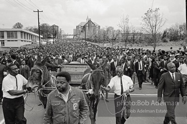 Free at last: King goes to his rest,  Atlanta, Georgia.   1968-


“With more than 50,000 mourners from all over the world following, King’s earthly remains were borne on a simple country wagon pulled by two mules. It was fitting: A wooden wagon was basic transport for the disadvantaged and disinherited, the people he served in his very public ministry. King’s life was dedicated to service. He studied, strategized, exhorted, prayed, marched, pleaded, protested, negotiated and spoke, all to remedy long-standing injustices. “In his Gehenna he suffered vilification, numerous jailings, ’round-the-clock telephone threats, stonings, several bombings, a stabbing, repeated beatings, cross burnings, nervous exhaustion and, finally, an assassin’s bullet. King died serving the dispossessed, and they understood this and adored him for it. Country people would and did drop to their knees as he passed, bawling out,     ‘de Lawd!’”