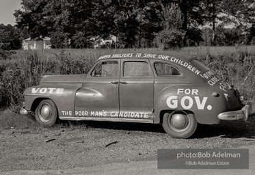 Campaign car left in field beside road. North of Baton Rouge, Louisiana, 1964.