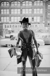 Silky goes shopping. Under his arm he carries material which he purchased to have five suits tailored to his own design. New York City, 1970. photo:©Bob Adelman. From the book Gentleman of Leisure by Susan Hall and Bob Adelman.