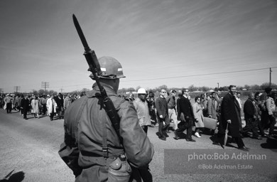 “With helicopters whirring above and the 54 miles of highway closely guarded by U.S. Army troops and the Alabama National Guard, the march into the Cradle of the Confederacy, Montgomery, was the greatest display of the power of the people’s right to peacefully petition since Gandhi’s Salt March to the sea. King’s ultimate faith in American justice was rewarded by the military’s
protection, by President Johnson’s vow that ‘we shall overcome’ and by Johnson’s call for passage of a voting rights bill.”  1965