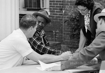 Having his say: An illiterate first-time voter casts his ballot orally under the provisions of the Voting Rights Act as an FBI agent looks on,  Camden,   Alabama.  1966-

“During the debate on the Voting Rights Act of 1965, Dr. King argued strenuously that illiterate blacks should have the right to cast their ballots orally. He justified his position by pointing out the poor quality of education offered in separate-but-equal schools.”