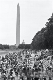 Marching along side the reflecting pool, protestors en route to the Lincoln Memorial with the Washington Monument and Capital Dome in the backround. Washington, D.C. August 28, 1963.