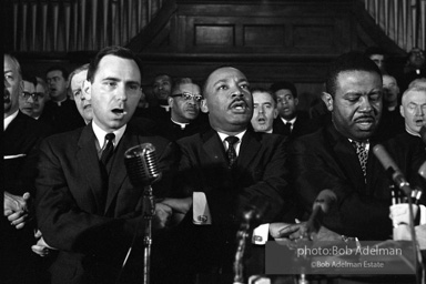 King leads the singing of “We Shall Overcome” after eulogizing a slain civil rights crusader, the Reverend James Reeb, Brown Chapel,  Selma,  Alabama.  1965