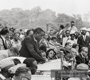 In national director James Farmer's absence Floyd McKissick, chairman of Core, addresses the March. Mrs. King and Dr. King are visible on the podium. Washington D.C. August 28, 1963.