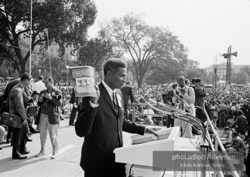 Ossie Davis, MC, at the assembly point near the Washington Mounument holds up the official poster for the March with Bob Adelman's Water Hosing photograph. August 28, 1963.