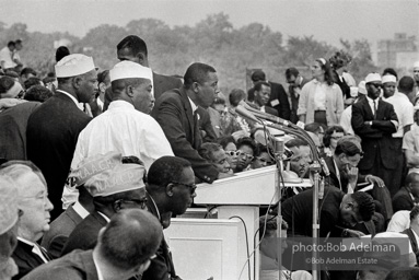 In national director James Farmer's absence Floyd McKissick, chairman of Core, addresses the March. Mrs. King and Dr. King are visible on the podium. Washington D.C. August 28, 1963.