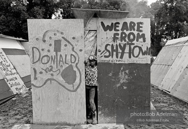 A boy poses next to signs that decorate the shantys in 