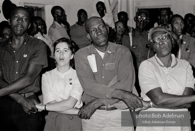 Joining the flock, West Feliciana Parish, Louisiana. 1963

“In West Feliciana, an overwhelmingly black parish where no person of color had voted in the twentieth century, volunteer Mimi Feingold urged members of a church congregation to try to vote. She then joined hands with them to sing, ‘This Little Light of Mine.