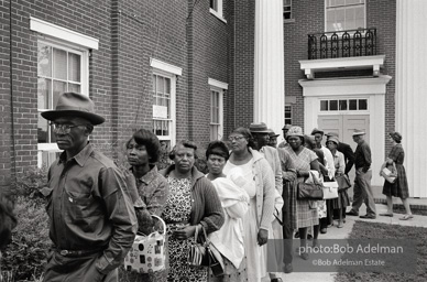 A new day dawns: Voters, most of them about to fill out their first-ever ballots, line up at the courthouse,  Camden, Alabama. 1966-

“The Voting Rights Act of 1965 changed everything, outlawing literacy tests and other barriers. It made it possible for thousands of black officials to eventually be elected in the South, and it certainly helped in
the election of two white southerners to the presidency. It was a large
factor in the gradual decrease of racial tension throughout the South. In a rare show of unity, more than forty years after the Voting Rights Act was passed, Congress renewed the measure unanimously.”