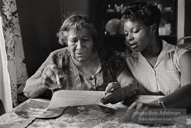 CORE volunteer helping an older woman learn to fill out a voter registration form,
East Feliciana Parish, LA 1963