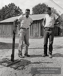 Two men looking at burnt cross West Feliciana Parish, LA 1963. The night after Rev. Joseph Carter became the first black person to register in West Feliciana Parish since the 1920s, crosses were burned across East and West Feliciana parishes by the KKK and its sympathizers.