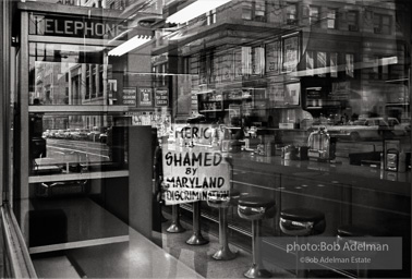 Reflection in the window of a downtown Baltimore segregated restaurant. Baltimore, MD. 1962