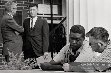 Elections official assisting a voter, Camden AL 1966. In this image, a local elections official is helping an illiterate voter by reading out the choices and marking his
ballot. Federal officials were on hand to oversee the election process and ensure fairness. In the background,
second from the left, is John Doar, Assistant US Attorney General for Civil Rights, who had monitored the Civil
Rights Movement since 1961. Doar later became Chief Counsel for the House Committee on the Judiciary during
the Watergate hearings. Elections official assisting a voter, Camden AL 1966. In this image, a local elections official is helping an illiterate voter by reading out the choices and marking his
ballot. Federal officials were on hand to oversee the election process and ensure fairness. In the background,
second from the left, is John Doar, Assistant US Attorney General for Civil Rights, who had monitored the Civil
Rights Movement since 1961. Doar later became Chief Counsel for the House Committee on the Judiciary during
the Watergate hearings.