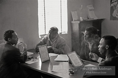 CORE worker Frank Robinson conducting voter education in his office, Sumter, SC 1962 Here Robinson instructs a small group of men on how to fill out the voter registration form.
On the desk are two framed examples of completed forms to which the men could refer.