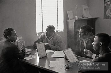 CORE worker Frank Robinson conducting voter education in his office, Sumter, SC 1962 Here Robinson instructs a small group of men on how to fill out the voter registration form.
On the desk are two framed examples of completed forms to which the men could refer. CORE worker Frank Robinson conducting voter education in his office, Sumter, SC 1962 Here Robinson instructs a small group of men on how to fill out the voter registration form.
On the desk are two framed examples of completed forms to which the men could refer.