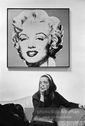 The artist Marisol Escobar at Robert Rauschenberg's studio under Andy Warhol's Marilyn Monroe. New York City, 1966.