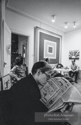 Andy Warhol reads the small ads in the Village Voice (Kay Bearman and Ivan Karp in background). Leo Castelli Gallery. New York City, 1965.