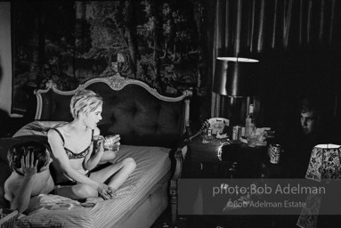 During Beauty #2, Edie Sedgwick answers questions from Chuck Wein off-camera in the shadows  while grappling with Gino Piserchio on the bed. New York City apartment, 1965.