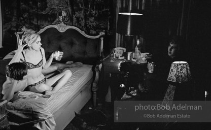 During Beauty #2, Edie Sedgwick answers questions from Chuck Wein off-camera in the shadows  while grappling with Gino Piserchio on the bed. New York City apartment, 1965.