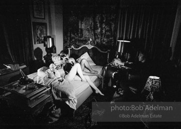 During Beauty #2, Edie Sedgwick answers questions from Chuck Wein off-camera in the shadows  while grappling with Gino Piserchio on the bed. New York City apartment, 1965.