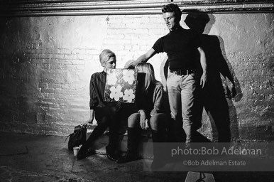 Gerard Malanga taking a light reading
using Flowers on the set of Prison. Edie Sedgwick and Bibbe Hanson (seated).The Factory, 1965.