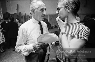 Party guest talks with Andy Warhol at a Factory party. 1965.