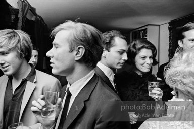 Chuck Wein, Andy Warhol at a society party. Marion Javitz (right, holding glass). New York City, 1965.