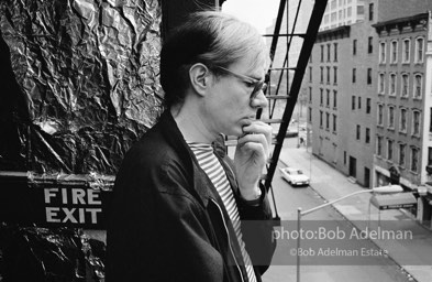 Andy Warhol on the Factory fire escape ouside of the Factory overlooking East 47th St. New York City, 1965.