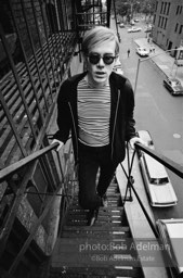 Andy Warhol on the Factory fire escape ouside of the Factory overlooking East 47th St. New York City, 1965.