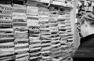 Andy Warhol browses the magazines at a news stand near Times Square. New York City, 1965.