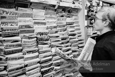 Andy Warhol browses the magazines at a news stand near Times Square. New York City, 1965.