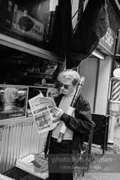 Andy Warhol reads the New York Times ouside a news stand. 1965.
