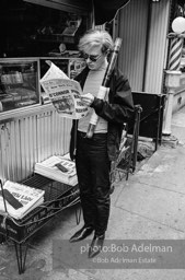 Andy Warhol reads the New York Times ouside a news stand. 1965.