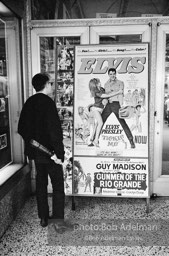 Warhol looks at a movie theater billboard in th Times Square area. New York City, 1965.