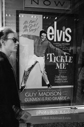 Warhol looks at a movie theater billboard in th Times Square area. New York City, 1965.